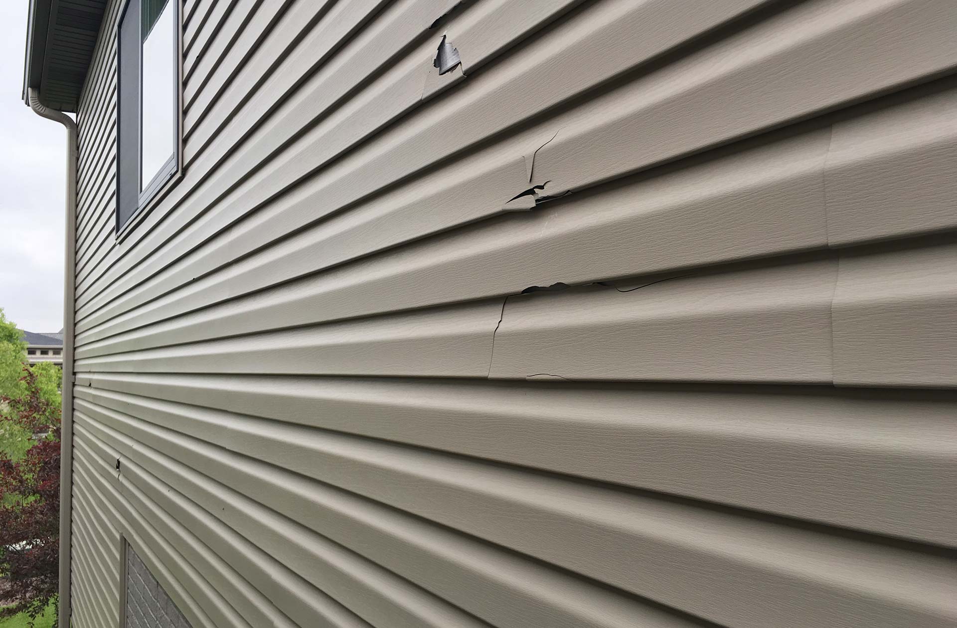 Cracked vinyl siding as a result of hail damage. 